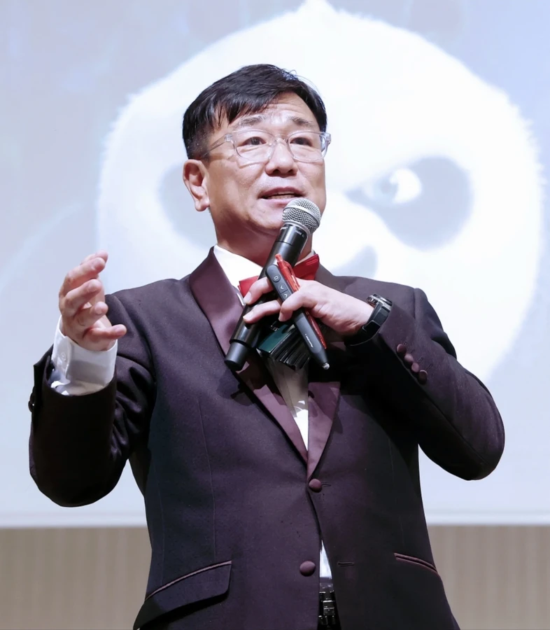 무대 조명 배경 앞에서 정장을 입고 마이크를 들고 말하는 사회자 클로즈업