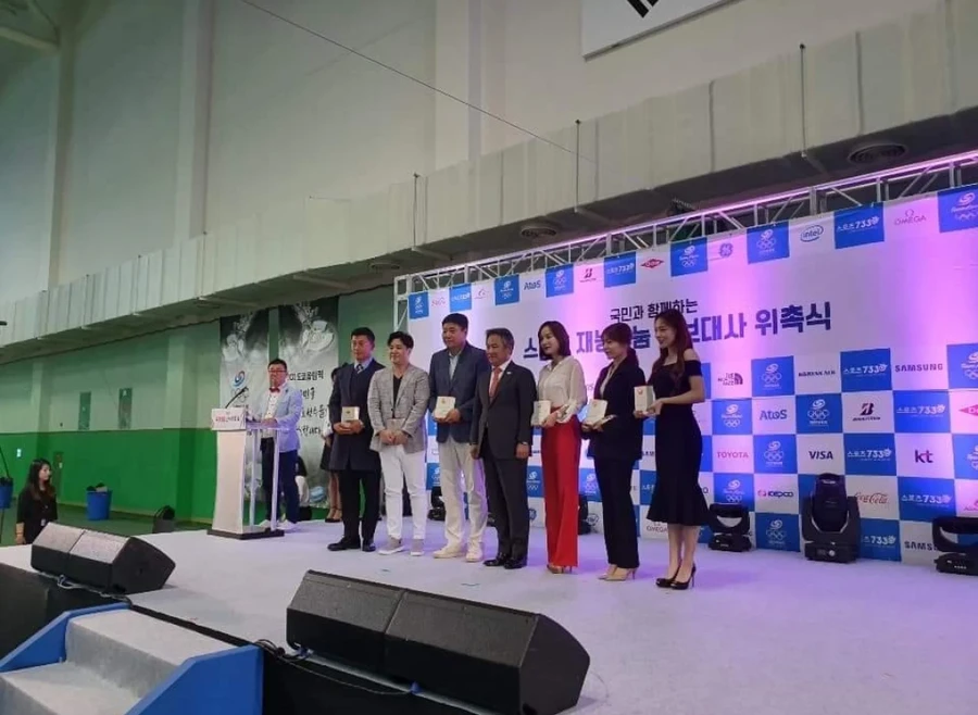 무대 위에서 위촉패를 들고 서 있는 정장 및 드레스 차림 참석자 단체 기념 촬영