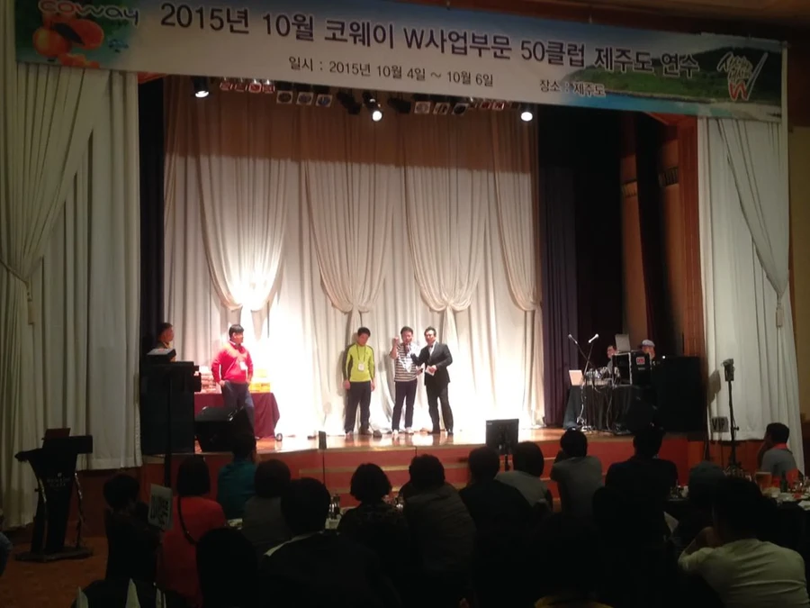 호텔 연회장 무대에서 시상 전달이 진행되고 객석에 참석자가 앉아있는 시상식 장면
