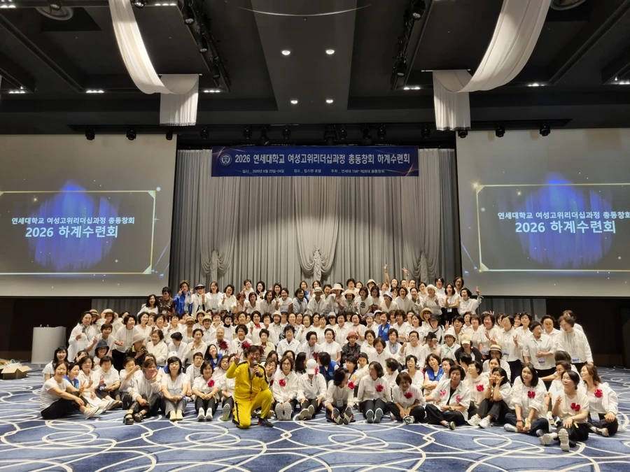 연회장 무대 앞에서 단체로 기념 촬영하는 참석자들