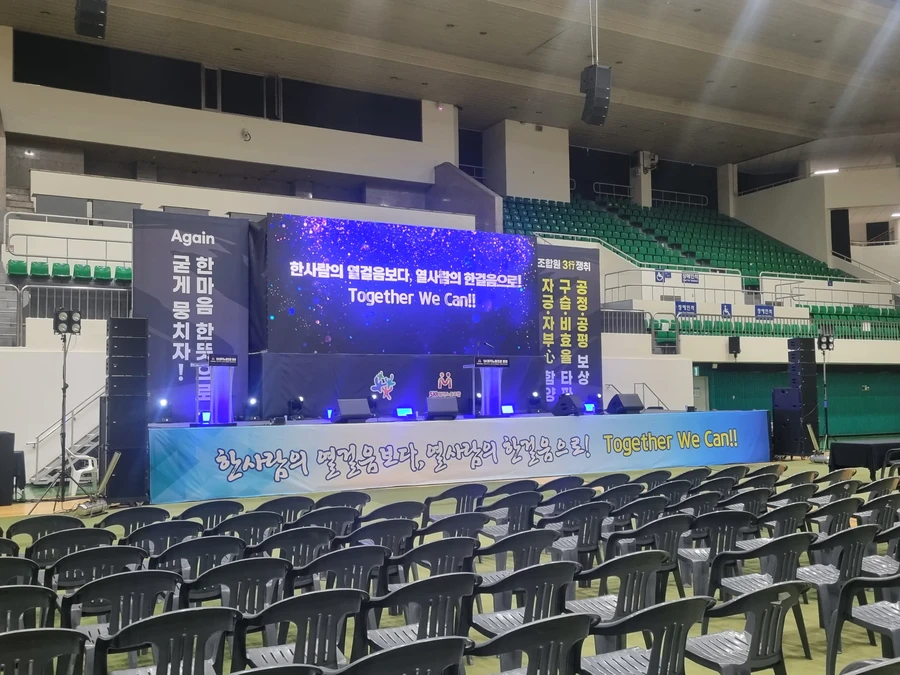 대형 스크린과 좌석이 정돈된 실내 행사장 무대 전경